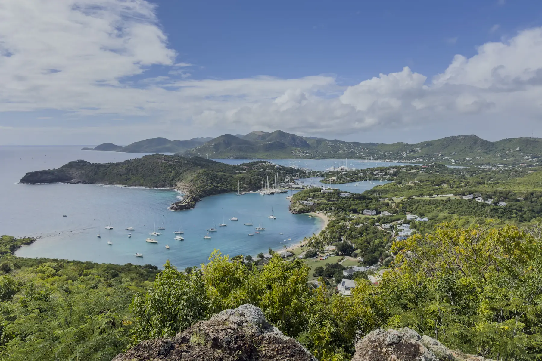 Zeilboten in een beschutte baai onder de groene heuvels van Antigua