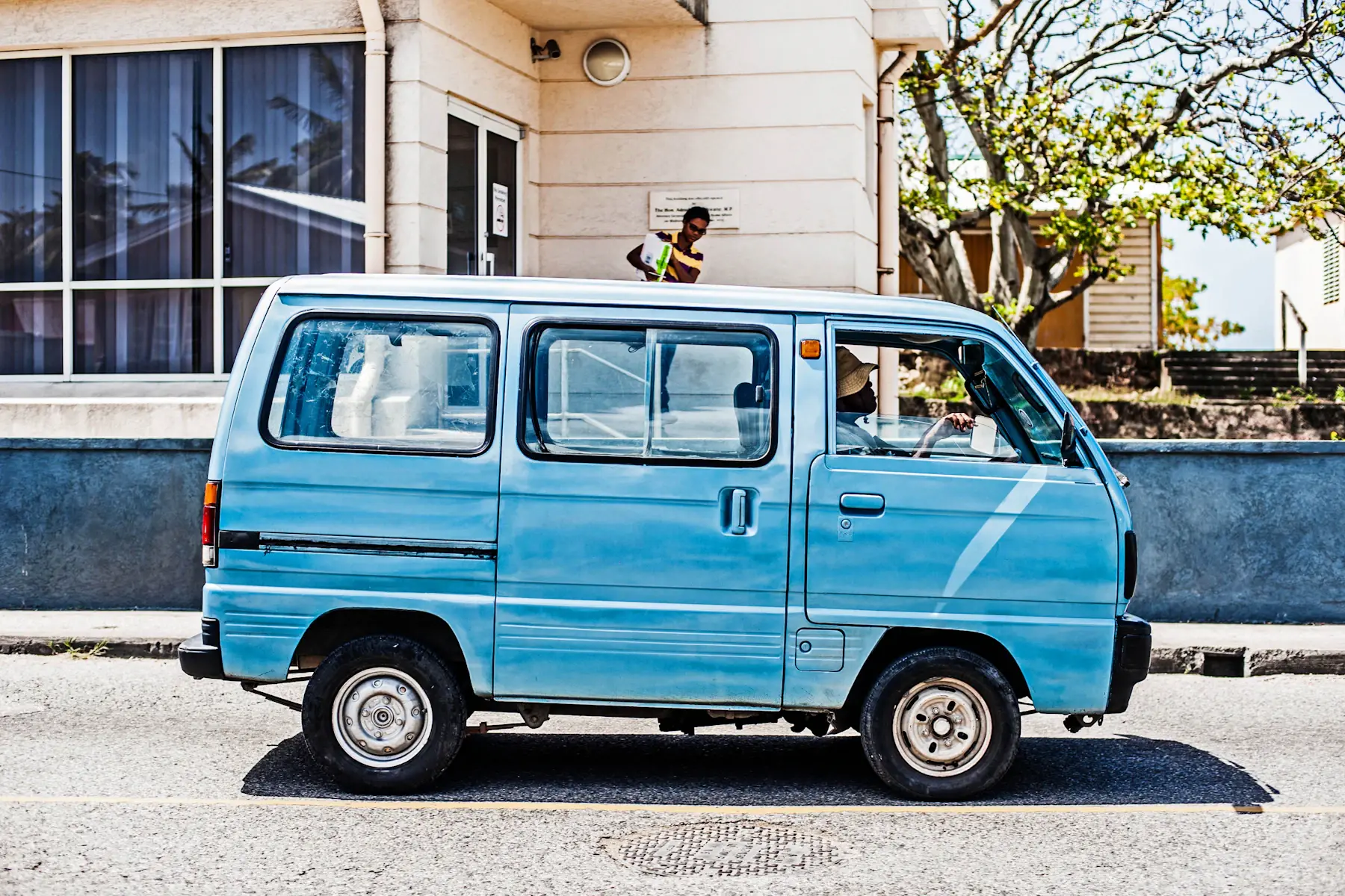 Een blauw voertuig langs een straat op Barbados