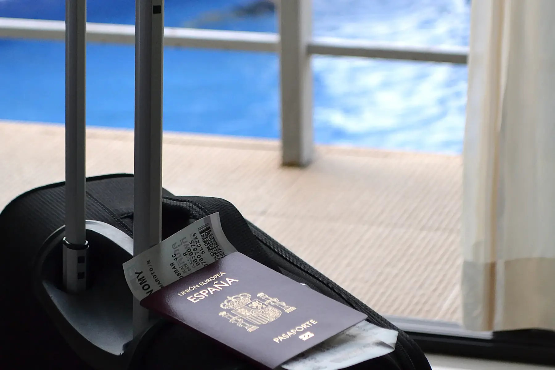 A suitcase with a passport and ticket beside a sunny balcony