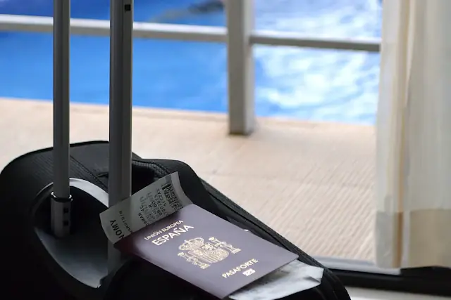 A suitcase with a passport and ticket beside a sunny balcony