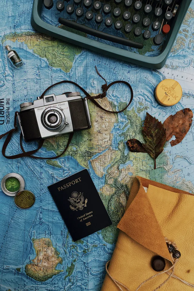 A passport, camera and travel items on a map